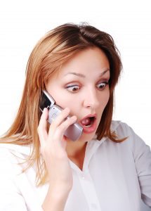 Young brunette with surprised expression on face speakin on cell phone - remodel contractor